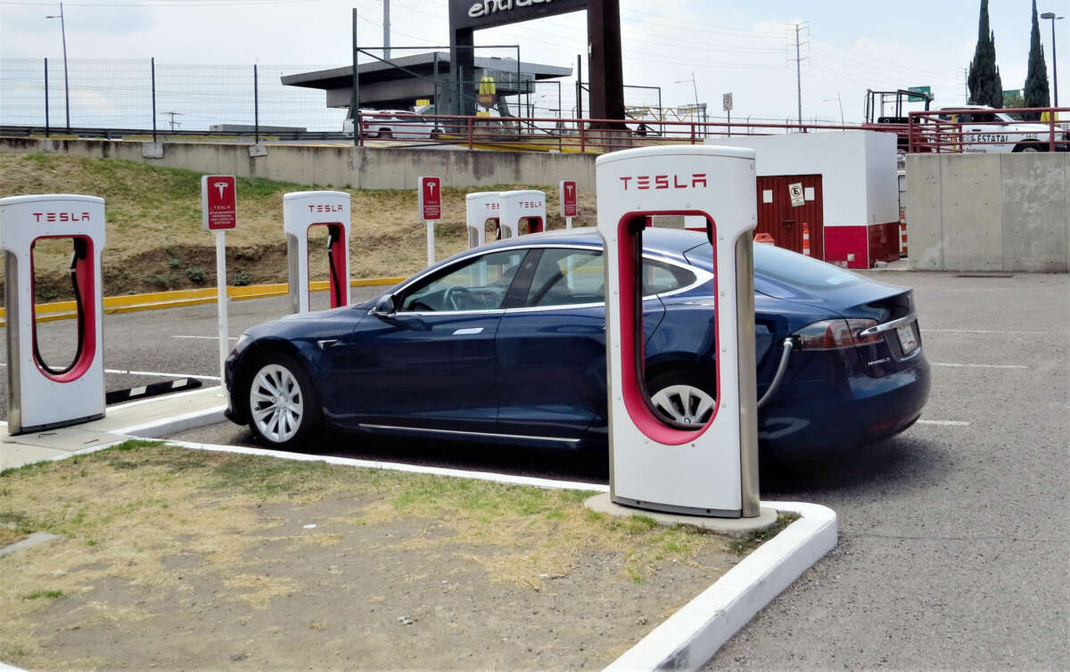 A blue car charges at a Tesla charging station