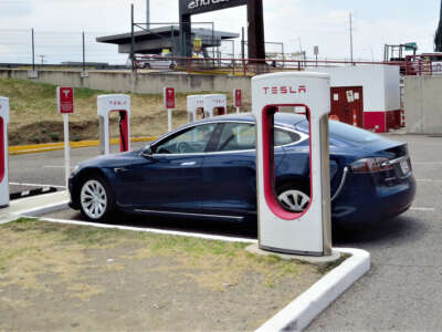 A blue car charges at a Tesla charging station