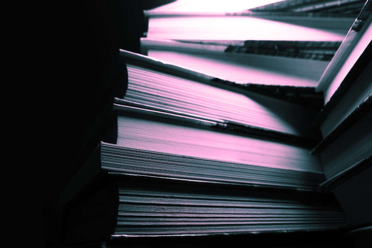 Stack of books in darkness lit with pink and blue light