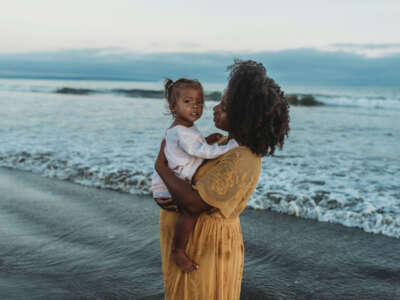 Pregnant mother and daughter in front of beach