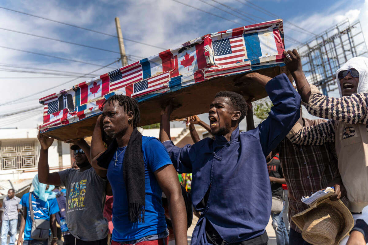 Haitians carry a coffin plastered in U.S., Canadian and French flags during an outdoor protest