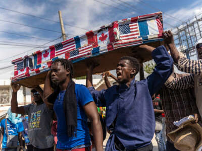 Haitians carry a coffin plastered in U.S., Canadian and French flags during an outdoor protest