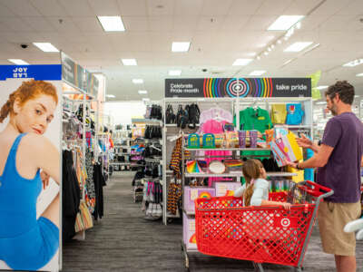 A dad pushes his child in a shopping cart through the Pride section of a Target's clothing department