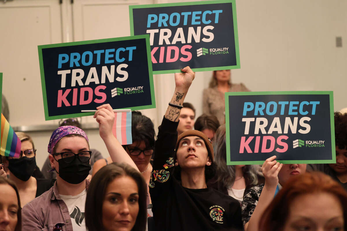 People hold signs during a joint board meeting of the Florida Board of Medicine and the Florida Board of Osteopathic Medicine, on November 4, 2022, in Lake Buena Vista, Florida, to establish new guidelines limiting gender-affirming care in Florida.