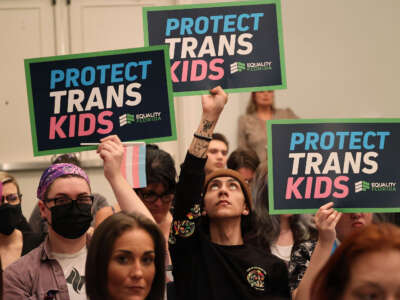 People hold signs during a joint board meeting of the Florida Board of Medicine and the Florida Board of Osteopathic Medicine, on November 4, 2022, in Lake Buena Vista, Florida, to establish new guidelines limiting gender-affirming care in Florida.