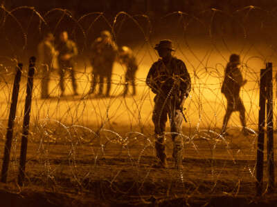 A Texas National Guard soldier stands vigil at a makeshift migrant camp near the U.S.-Mexico border fence on May 11, 2023, in El Paso, Texas.