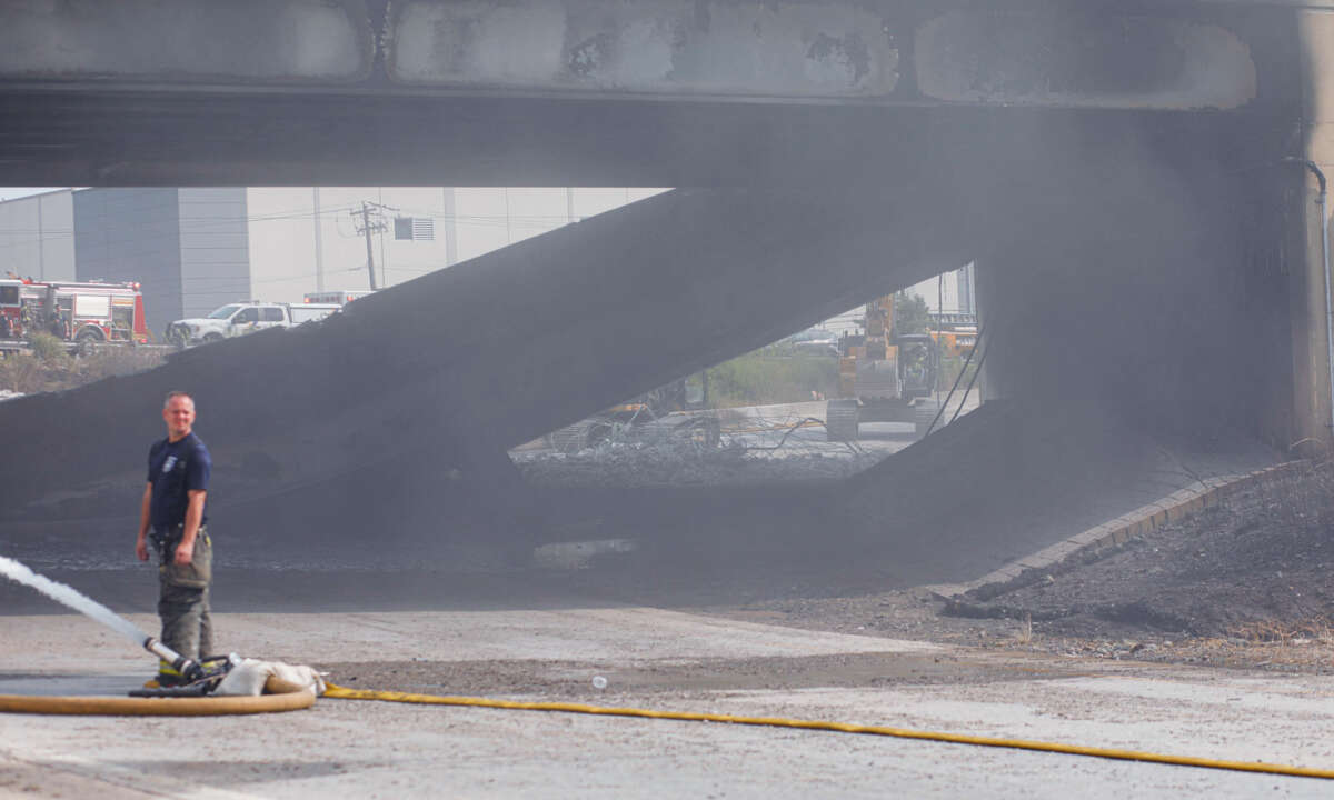 A fireman looks around while emergency crews clear the wreckage of a highway collapse behind him