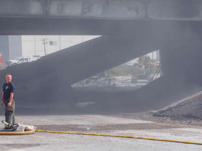 A fireman looks around while emergency crews clear the wreckage of a highway collapse behind him