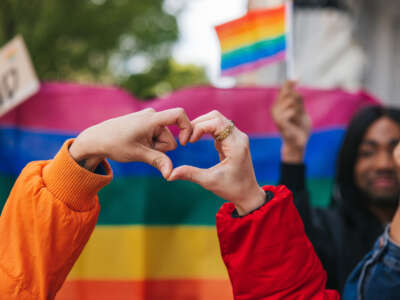 LGBTQ demonstration with pride flags and two people making a heart with their hands