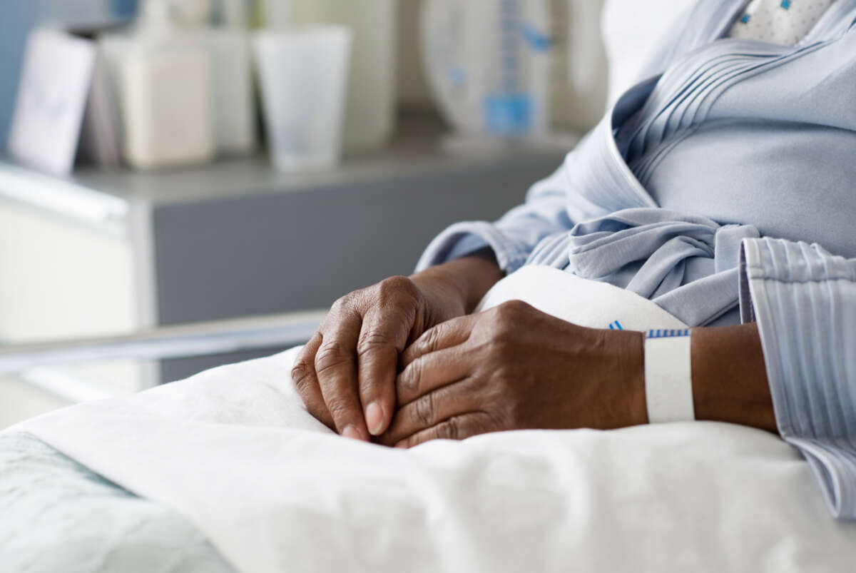 Black woman patient's hands in hospital bed