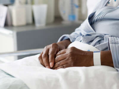 Black woman patient's hands in hospital bed