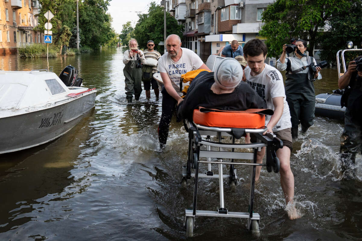 Volunteers are seen pushing a medical bed as people are evacuated from Kardashinka, the territory occupied by the Ukrainian armed force, as flooding continues to affect some areas in the city after the destruction of the Kakhovka dam, on June 9, 2023.