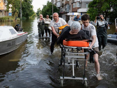 Volunteers are seen pushing a medical bed as people are evacuated from Kardashinka, the territory occupied by the Ukrainian armed force, as flooding continues to affect some areas in the city after the destruction of the Kakhovka dam, on June 9, 2023.