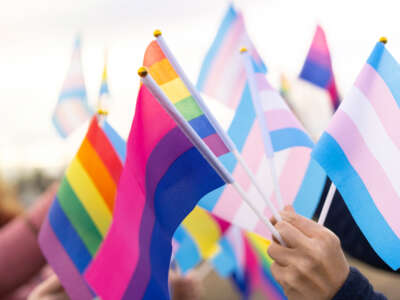 People hold small LGBTQ pride flags