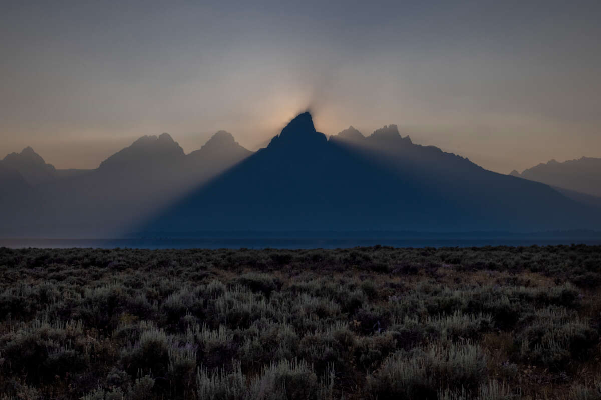 The sun sets behind the Grand Teton peak, shrouded in smoke from regional wildfires on July 14, 2021, at Grand Teton National Park.