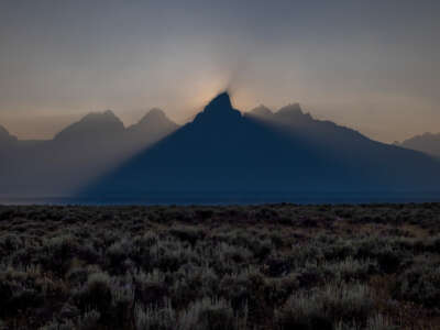 The sun sets behind the Grand Teton peak, shrouded in smoke from regional wildfires on July 14, 2021, at Grand Teton National Park.