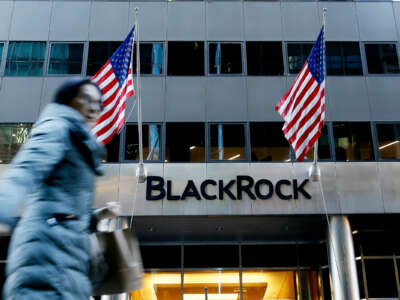 People walk past an office building labeled "BLACKROCK"