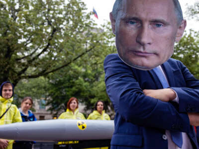 A protester wearing an oversized mask of Russian Prime Minister Vladimir Putin's head stands in front of other protesters carrying a fake nuclear warhead