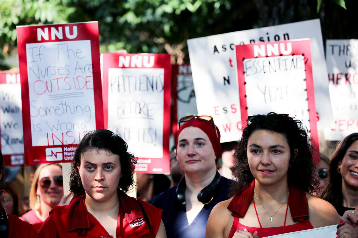 People dressed in red display signs supporting nurses during an outdoor strike