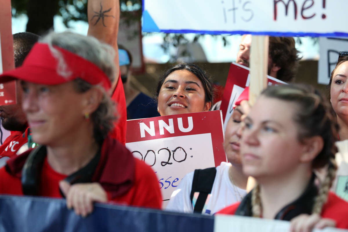 People dressed in red display signs supporting nurses during an outdoor strike