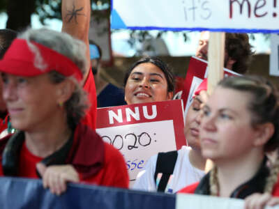 People dressed in red display signs supporting nurses during an outdoor strike