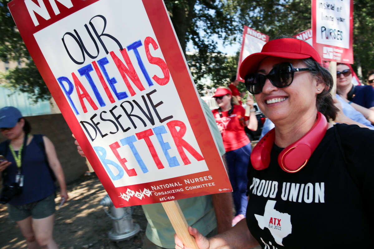 Registered nurse holding her hand-lettered sign reading "OUR PATIENTS DESERVE BETTER" during an outdoor demonstration