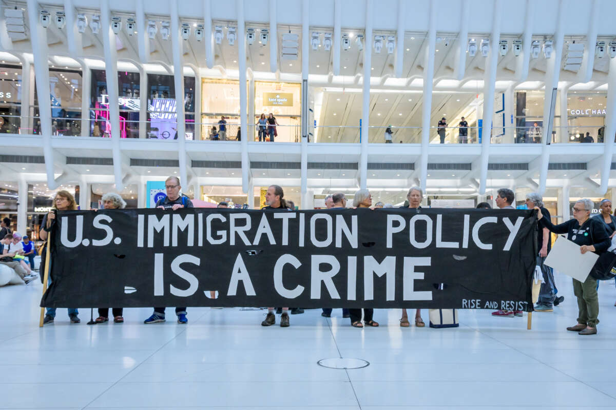 Activists hold a sign that says "U.S. Immigration Policy Is a Crime"