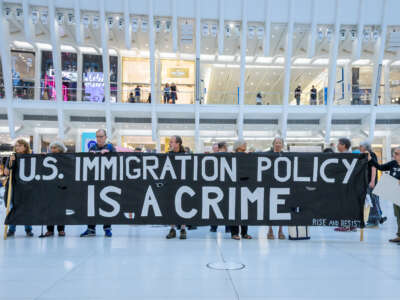 Activists hold a sign that says "U.S. Immigration Policy Is a Crime"