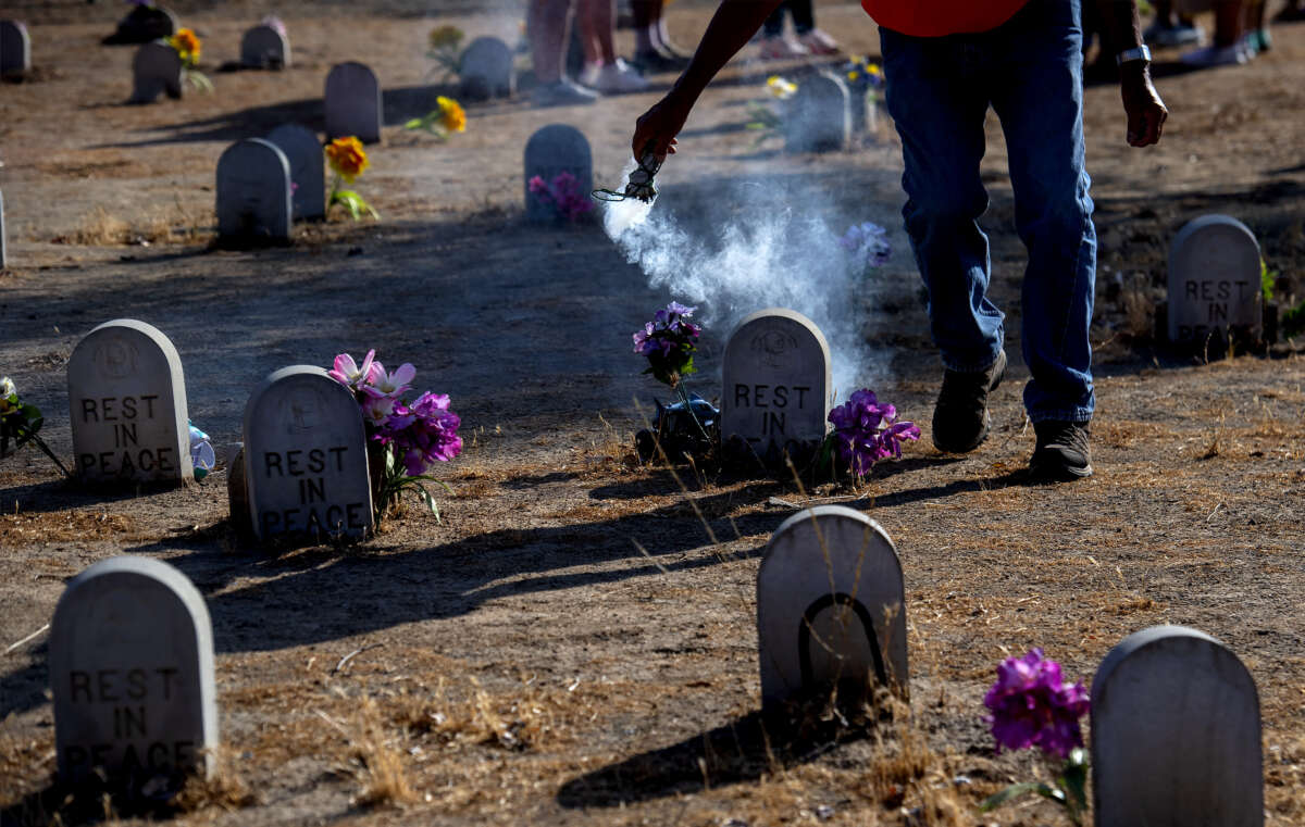 Dan Romero or Walking Bird of the Ute Tribe encircles the graves with sage smoke at Sherman Indian School Cemetery in Riverside, California, on Sunday, July, 18, 2021.