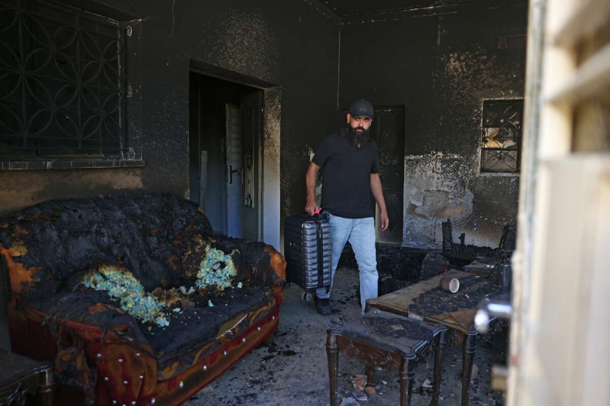 Palestinian Bilal Hijaz carries his luggage out of his home, which was set on fire by Israeli settlers the day before, in Turmus Ayya near the occupied West Bank city of Ramallah, on June 22, 2023.