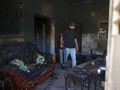 Palestinian Bilal Hijaz carries his luggage out of his home, which was set on fire by Israeli settlers the day before, in Turmus Ayya near the occupied West Bank city of Ramallah, on June 22, 2023.