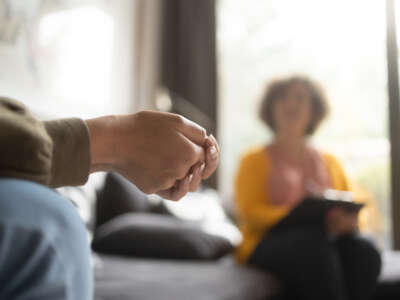 Close-up of a teenager's hands with fingers crossed nervously in a psychotherapy session