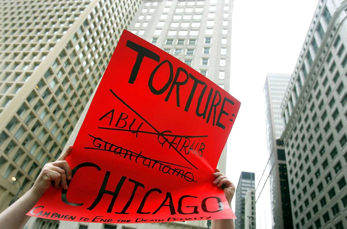 Adam Turl displays a sign protesting police torture during a demonstration on July 21, 2006 in downtown Chicago, Illinois.