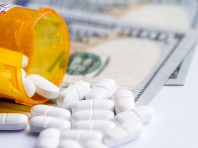 close up of a prescription bottle with white tablets falling out on top of a group of hundred dollar bills