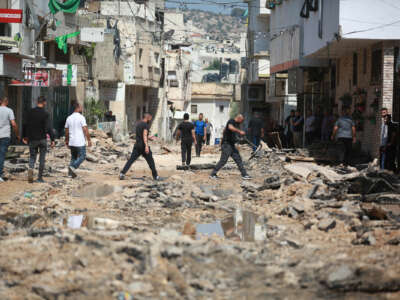 People walk through the rubble that was once a residential street