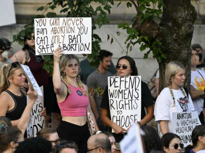 A protester holds a sign reading "YOU CAN'T BAN ABORTION, YOU CAN ONLY BAN SAFE ABORTION" during an outdoor protest