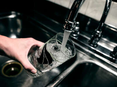 Water is poured into a glass from a faucet