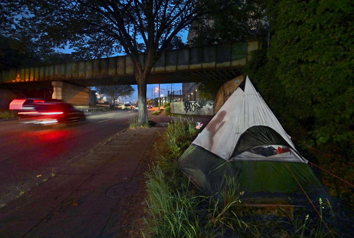 An unhoused person smokes a cigarette at dusk at her new campsite on a spot near a rail bridge overpass on New York Ave. in Washington, D.C., on May 12, 2023.