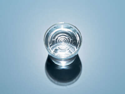 Bright Ripples on Water in a Glass Cup on Blue Background High Angle View.