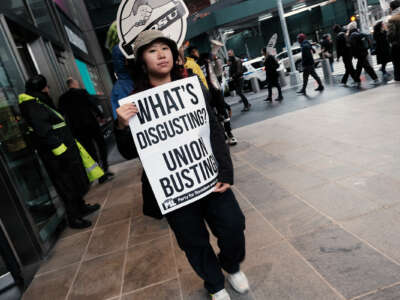 A protester holds a sign reading "WHAT'S DISGUSTING? UNION BUSTING" during an outdoor protest