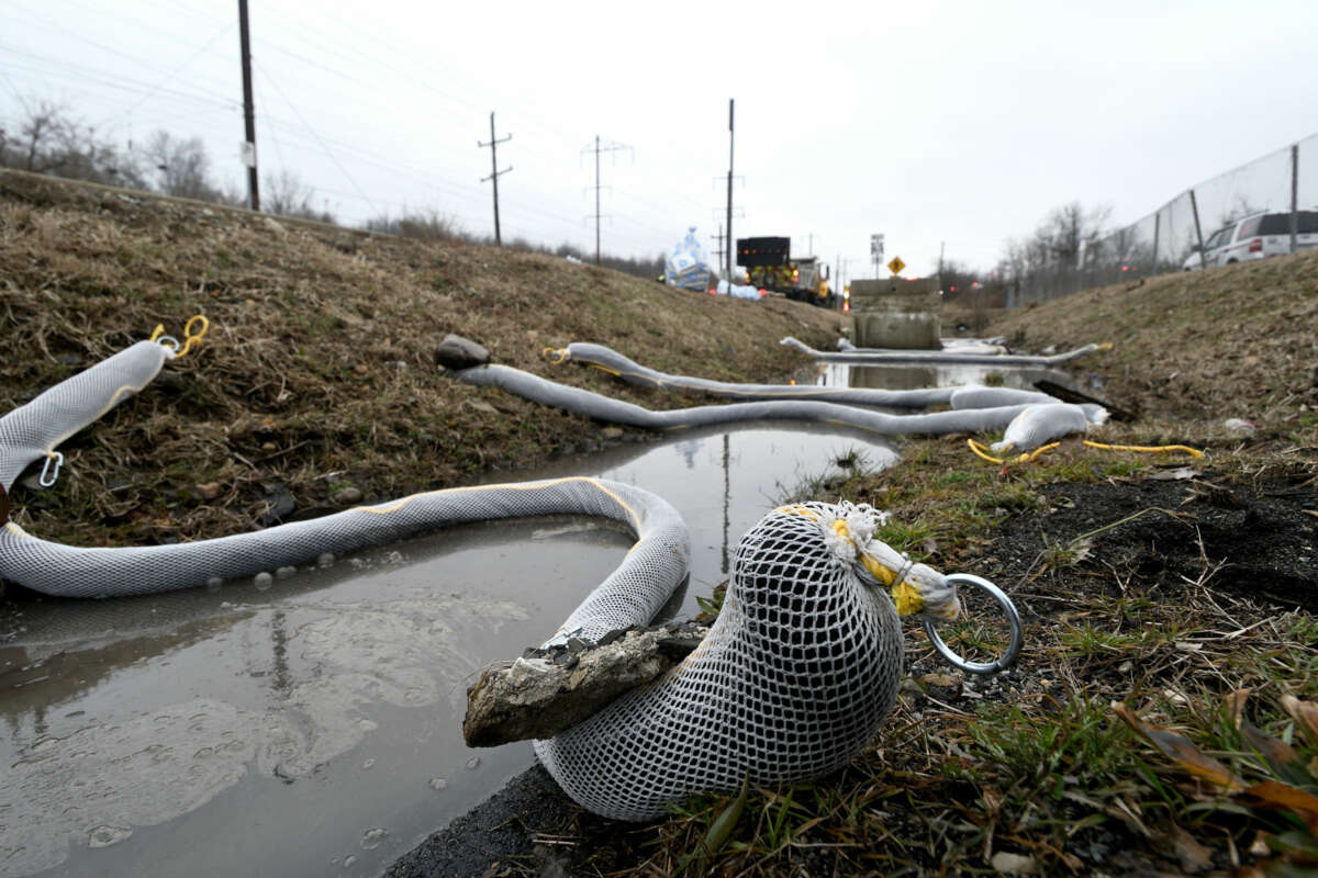 snake-like tubes of absorbent mesh are strewn across a polluted creek