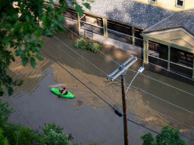 A man kayaks down a completely flooded residential street