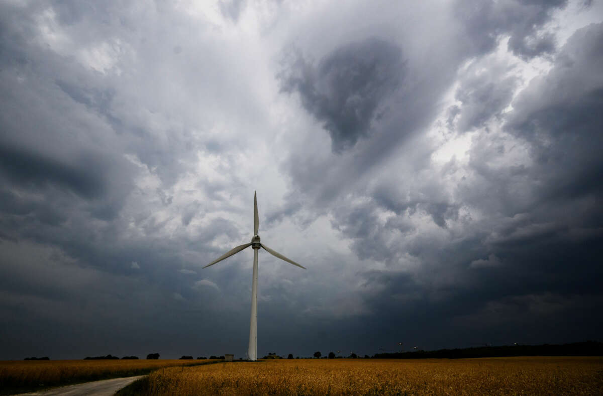 A lone wind turbine stands against cloudy skies