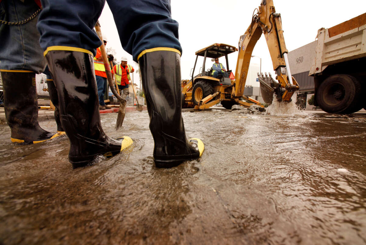 Department of Water and Power workmen use a backhoe to dig through the pavement to isolate a 12-inch water main that ruptured on Fairfax Avenue at the intersection of San Vicente Boulevard in the Miracle Mile area in Los Angeles, California, in September, 2009.