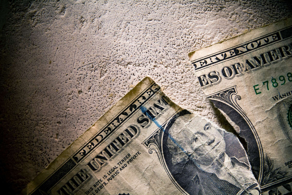 A photo of a United States Dollar lying dirty and torn on concrete