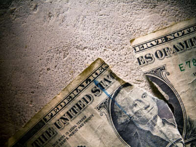 A photo of a United States Dollar lying dirty and torn on concrete