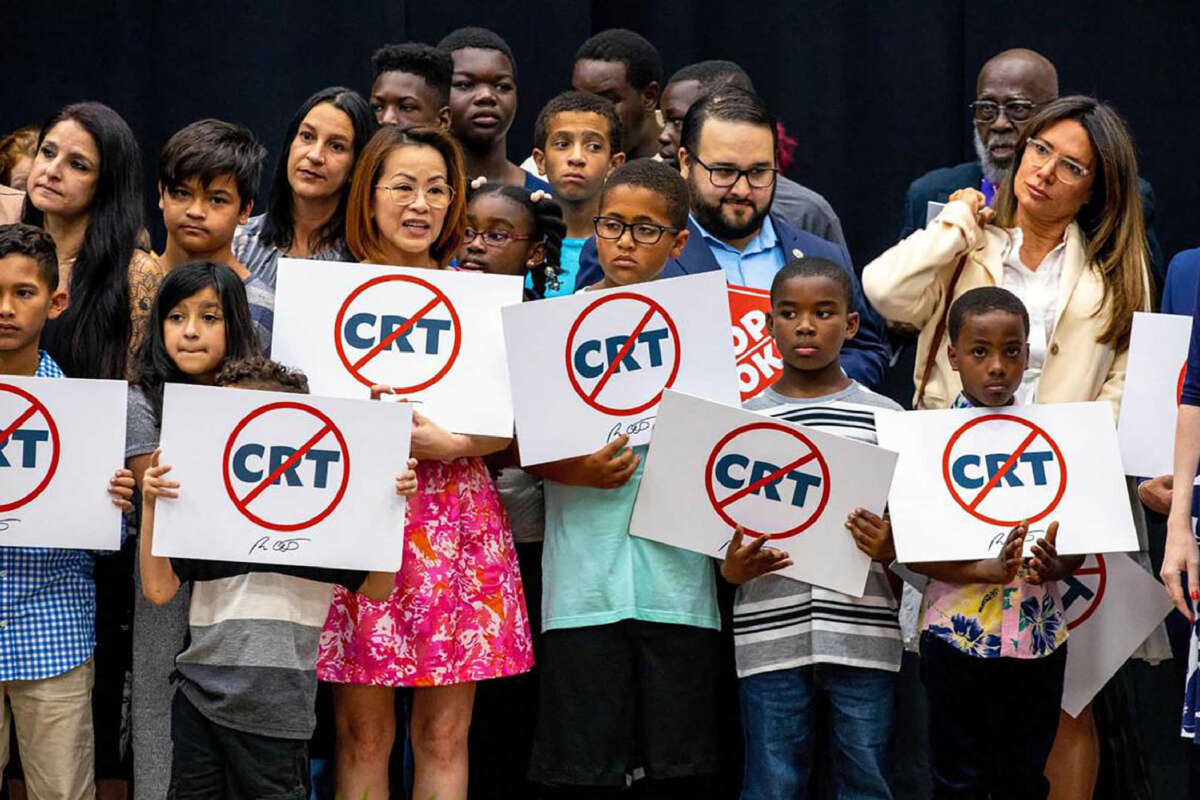 Schoolchildren holding signs against the concept of critical race theory stand on stage alongside Florida Gov. Ron DeSantis as he addresses the crowd during a news conference at Mater Academy Charter Middle/High School in Hialeah Gardens, Florida, on April 22, 2022.