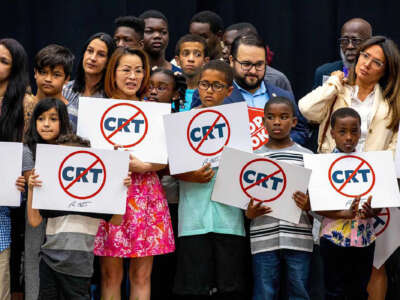 Schoolchildren holding signs against the concept of critical race theory stand on stage alongside Florida Gov. Ron DeSantis as he addresses the crowd during a news conference at Mater Academy Charter Middle/High School in Hialeah Gardens, Florida, on April 22, 2022.