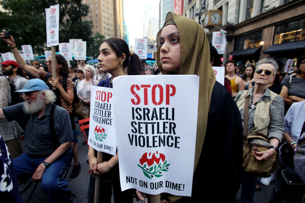 A protester holds a sign reading "STOP ISRAELI SETTLER VIOLENCE; NOT ON OUR DIME" during an outdoor demonstration