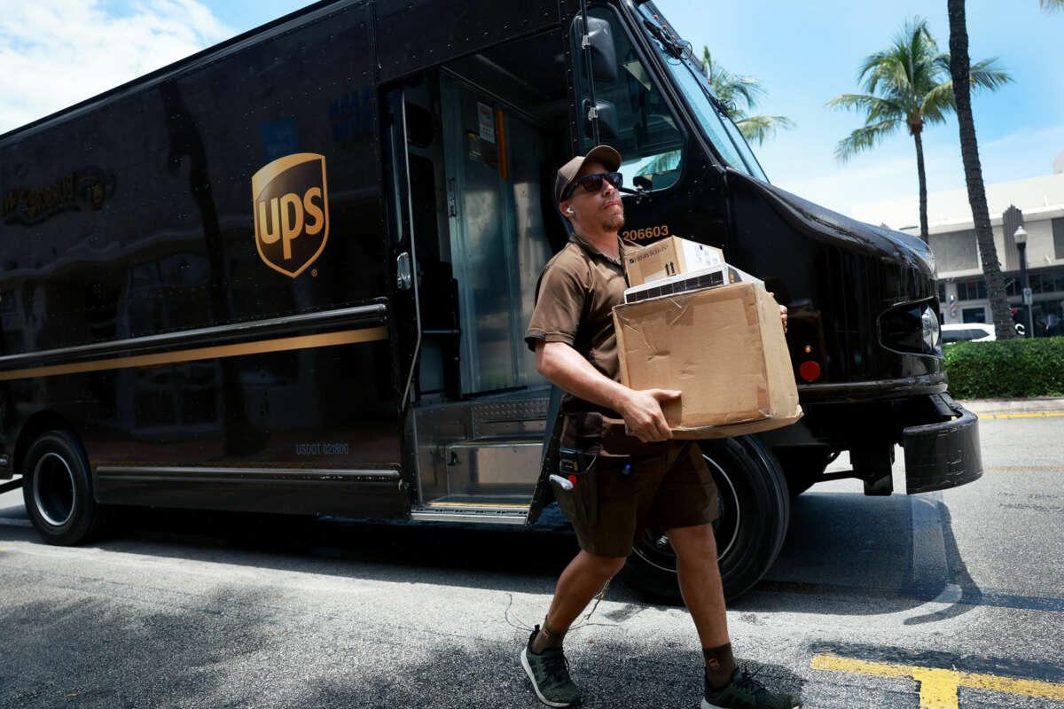 A UPS delivery driver carries packages to their destination